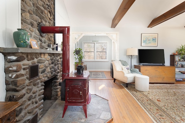 living area featuring hardwood / wood-style floors, beam ceiling, and a large fireplace