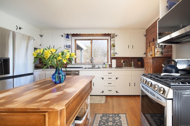 kitchen with light wood finished floors, light countertops, appliances with stainless steel finishes, white cabinetry, and a sink