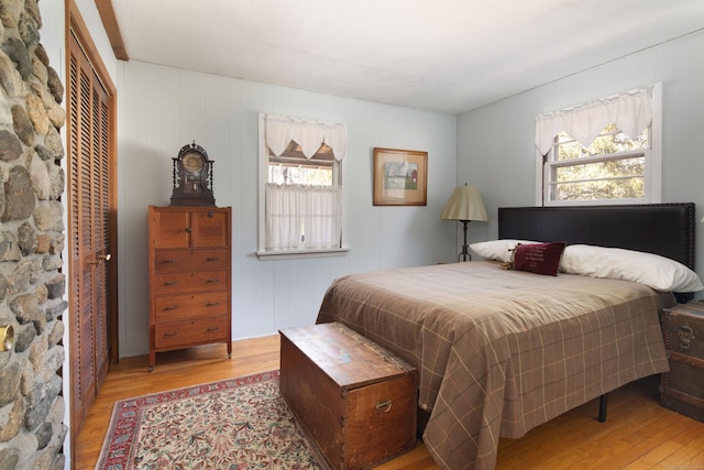 bedroom with multiple windows, wood finished floors, and a closet