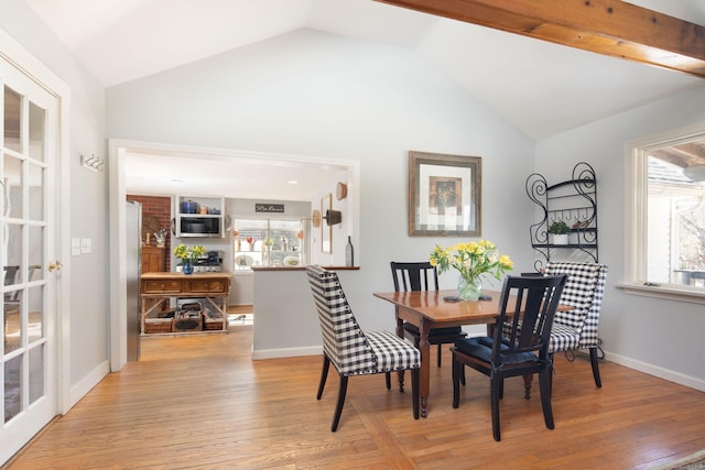 dining room featuring light wood-type flooring, baseboards, and vaulted ceiling