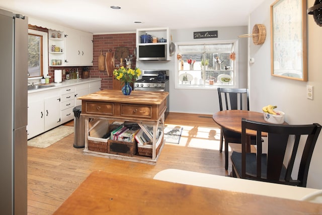 kitchen with appliances with stainless steel finishes, white cabinetry, light wood-type flooring, and open shelves