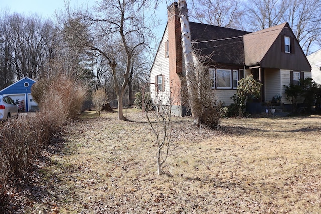 view of side of property with a chimney and roof with shingles