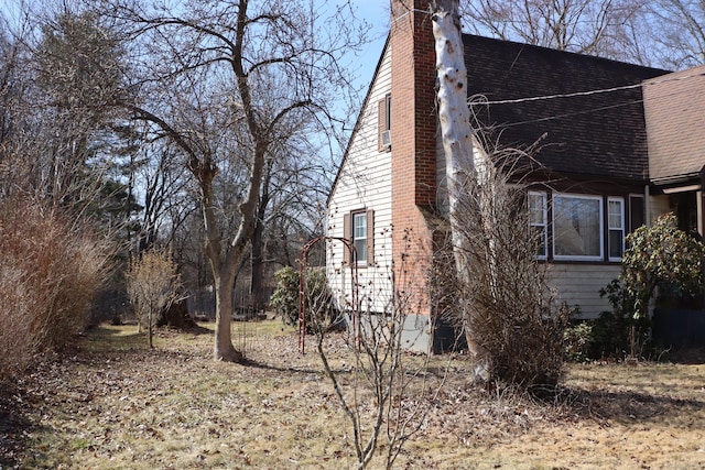 view of side of property featuring a chimney and roof with shingles