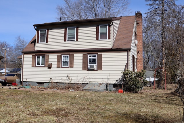 back of property with a chimney and a yard