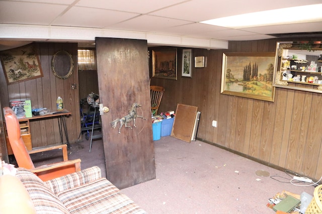 finished below grade area with wood walls, a paneled ceiling, and carpet