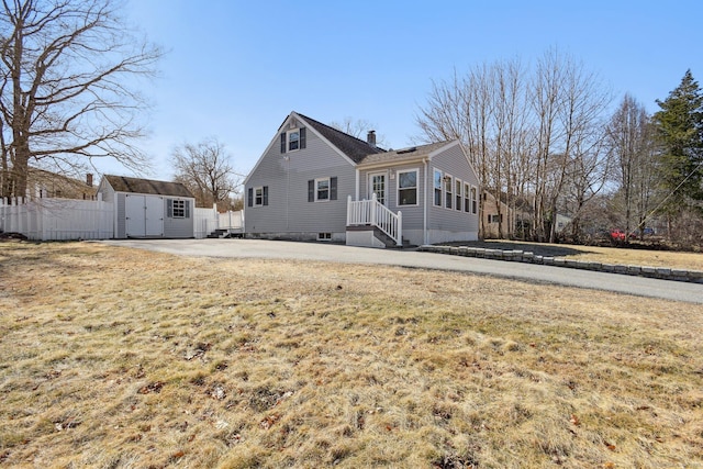 exterior space with fence, a front yard, a chimney, a storage shed, and an outbuilding