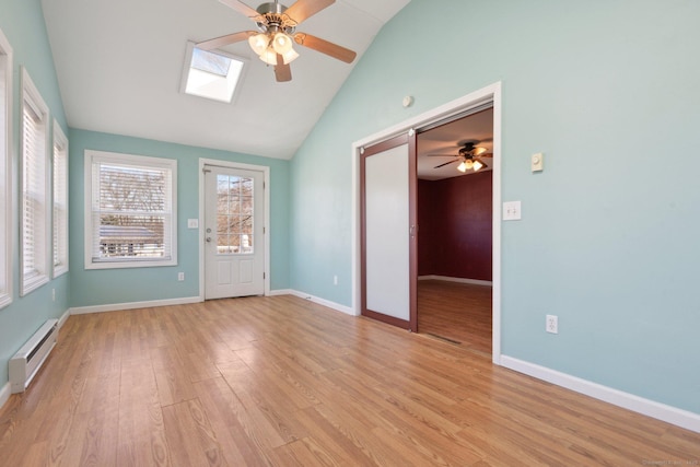 spare room with light wood-type flooring, a baseboard radiator, baseboards, and lofted ceiling with skylight