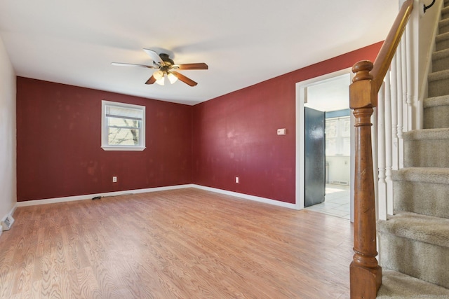 spare room featuring a ceiling fan, light wood-style floors, and stairs