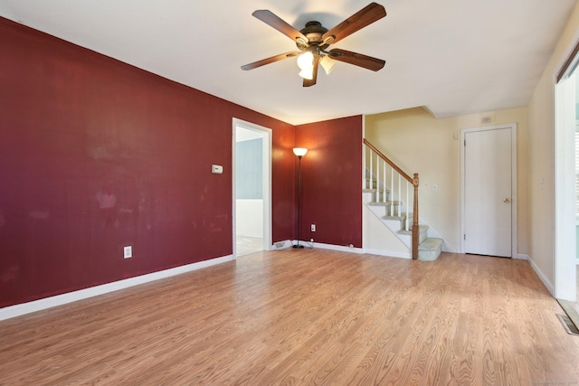 unfurnished living room with light wood finished floors, stairway, ceiling fan, and baseboards