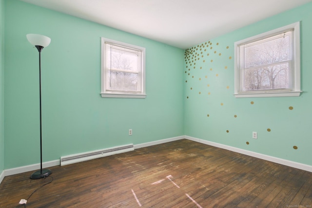 empty room featuring baseboards, wood-type flooring, and baseboard heating