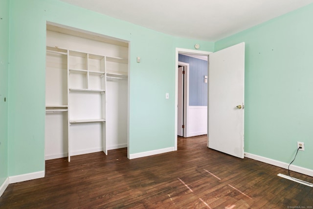 unfurnished bedroom with a closet, baseboards, and hardwood / wood-style flooring