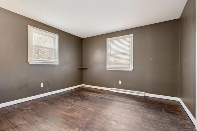 empty room featuring a baseboard radiator, baseboards, and wood finished floors