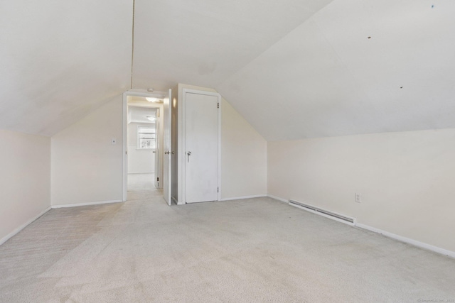 additional living space featuring vaulted ceiling, light carpet, baseboards, and a baseboard radiator