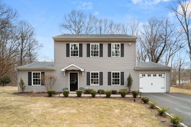 view of front of home with aphalt driveway, a front lawn, roof with shingles, and an attached garage