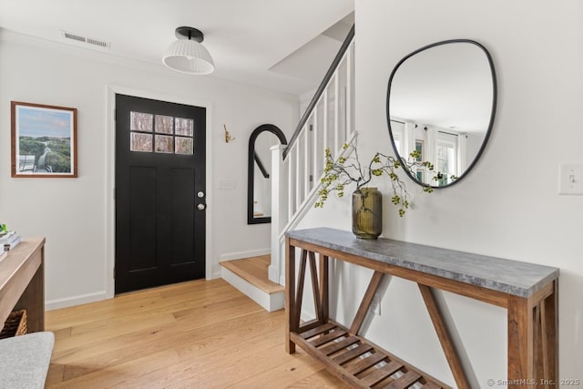 entryway featuring visible vents, stairs, light wood-type flooring, and baseboards