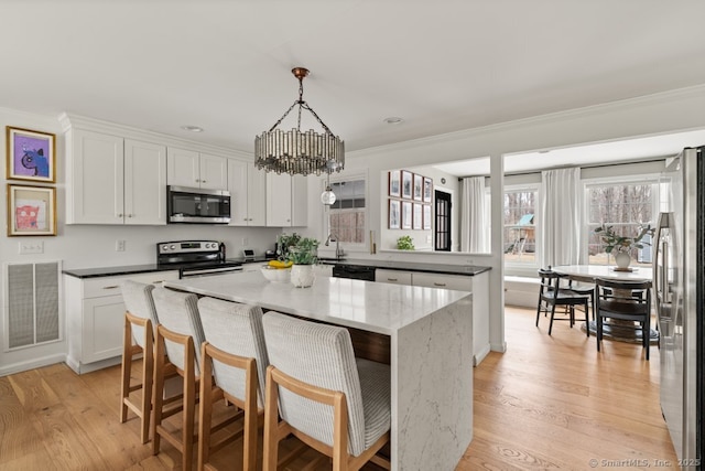 kitchen with visible vents, a center island, light wood-style floors, appliances with stainless steel finishes, and a peninsula