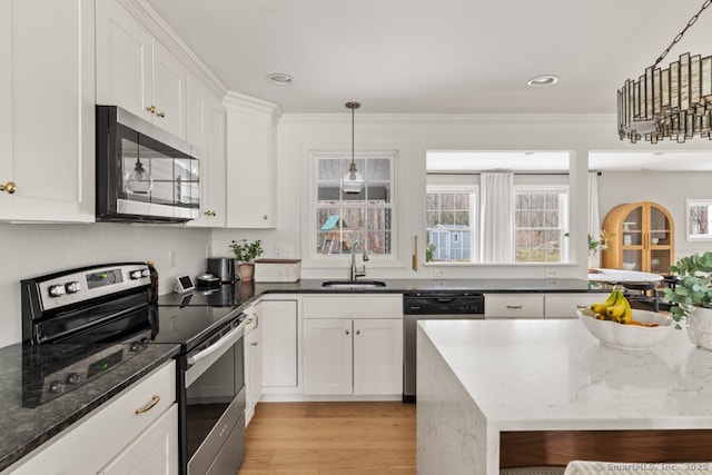 kitchen with light wood-style flooring, a sink, dark stone countertops, white cabinetry, and stainless steel appliances