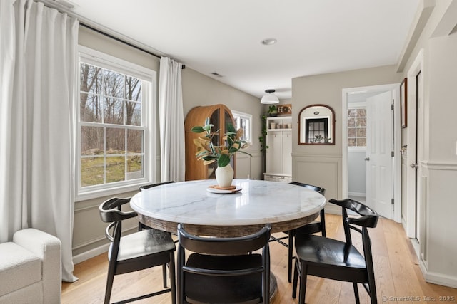 dining space with light wood-style flooring, plenty of natural light, visible vents, and baseboards