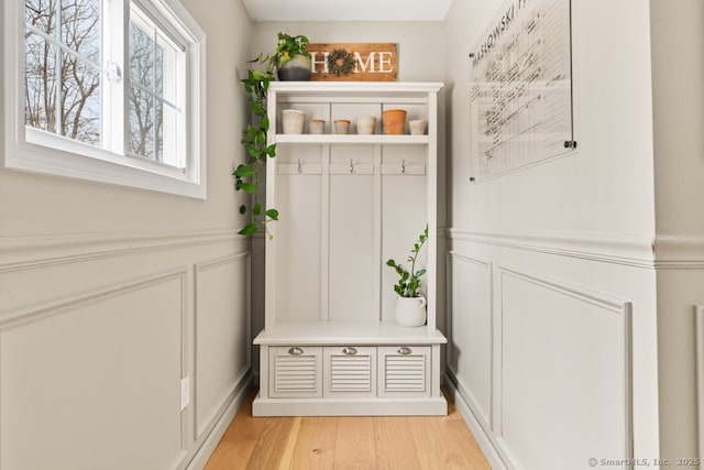 mudroom featuring a decorative wall, light wood finished floors, and wainscoting