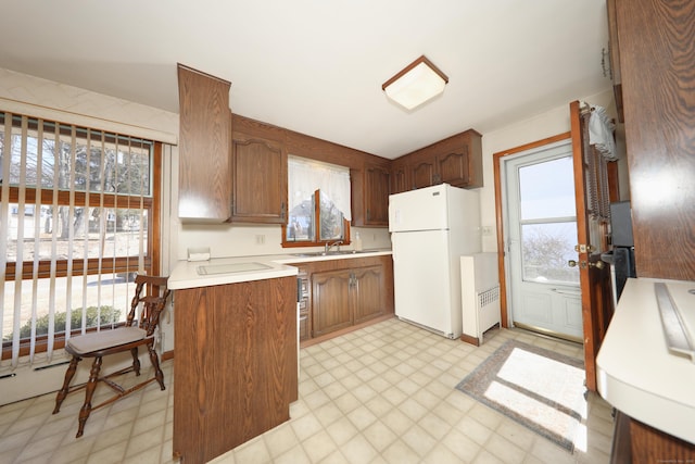 kitchen featuring light floors, light countertops, freestanding refrigerator, plenty of natural light, and a sink