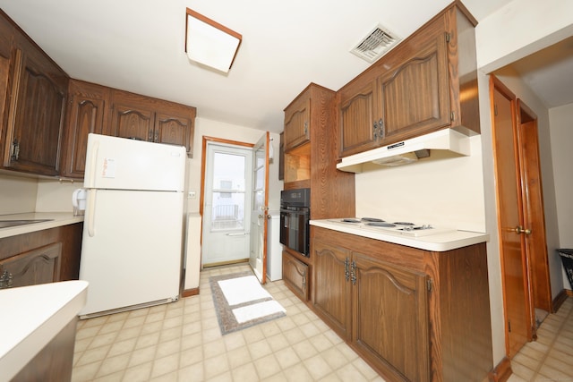 kitchen featuring visible vents, under cabinet range hood, light floors, light countertops, and white appliances