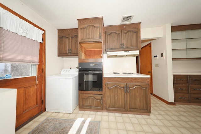 kitchen with visible vents, oven, under cabinet range hood, white stovetop, and washer / dryer