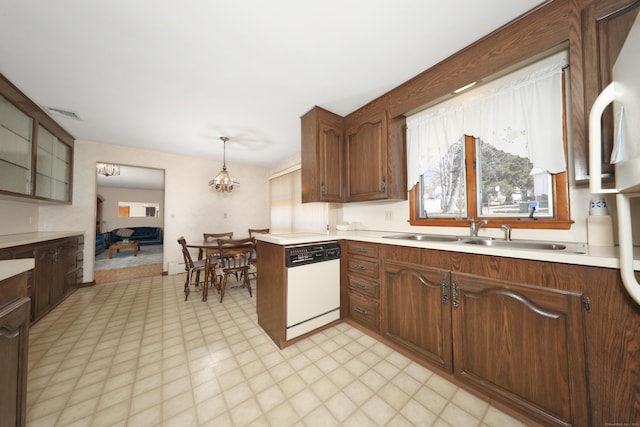 kitchen with light floors, white dishwasher, a sink, light countertops, and decorative light fixtures