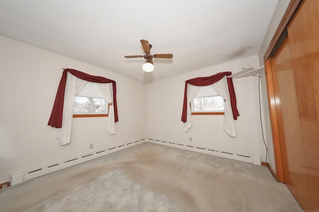 empty room with plenty of natural light, carpet flooring, a ceiling fan, and a baseboard radiator