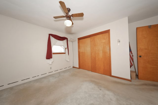 unfurnished bedroom featuring light carpet, a closet, baseboards, baseboard heating, and ceiling fan