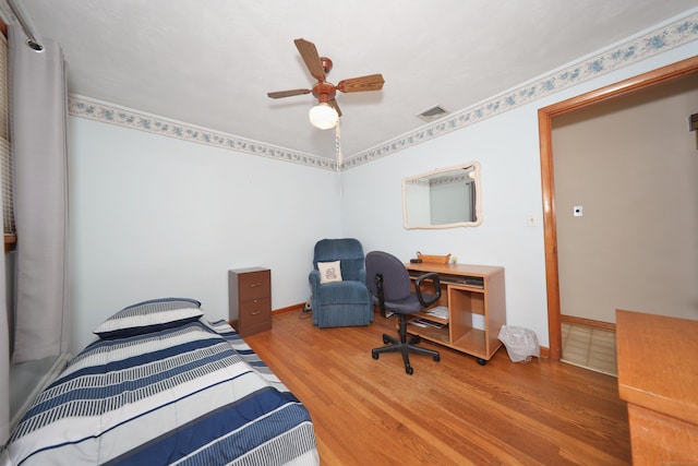 bedroom with a ceiling fan, wood finished floors, visible vents, and baseboards