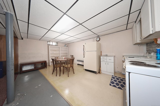 kitchen featuring white appliances, radiator, a sink, white cabinets, and a paneled ceiling