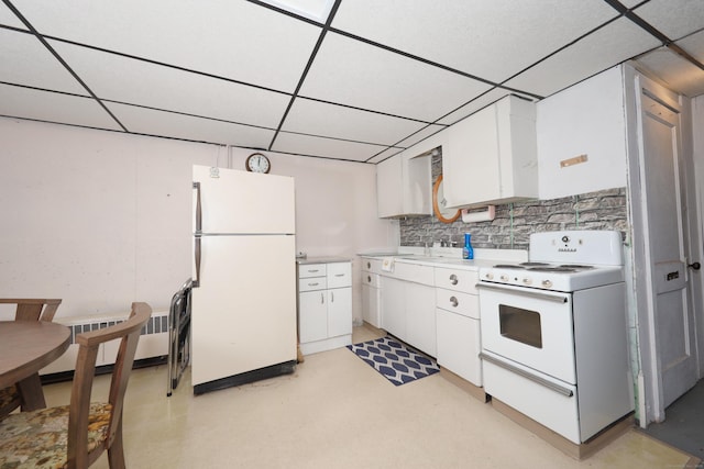 kitchen with white appliances, radiator heating unit, a drop ceiling, light countertops, and white cabinetry