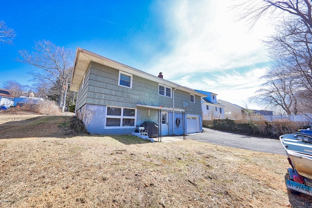 back of house featuring aphalt driveway and an attached garage