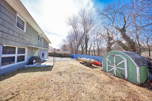 view of yard with an outbuilding, fence, a shed, and a patio area