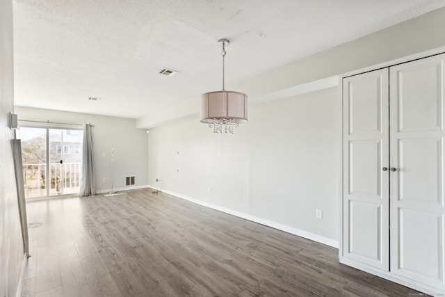 interior space featuring baseboards, wood finished floors, visible vents, and a textured ceiling