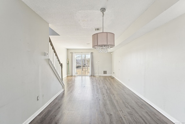 interior space with a textured ceiling, stairs, baseboards, and wood finished floors