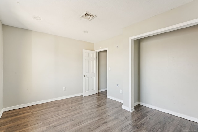 unfurnished bedroom with visible vents, baseboards, and wood finished floors