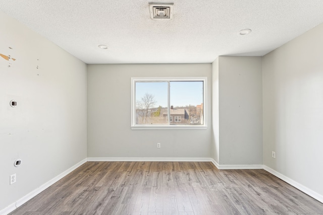 spare room featuring wood finished floors, baseboards, and a textured ceiling