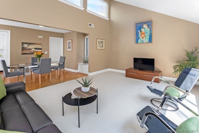 living room featuring visible vents, baseboards, a high ceiling, and wood finished floors