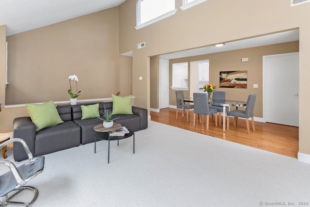 living area featuring wood finished floors, visible vents, and a towering ceiling