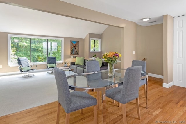 dining space with visible vents, baseboards, light wood-type flooring, and lofted ceiling