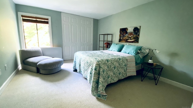 carpeted bedroom featuring baseboards and a closet