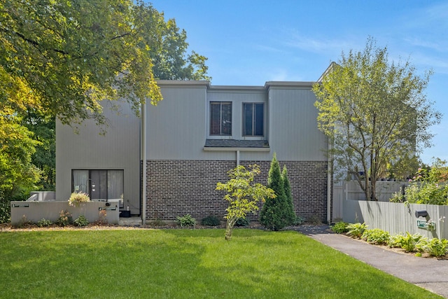 view of front of home with brick siding, a front lawn, and fence