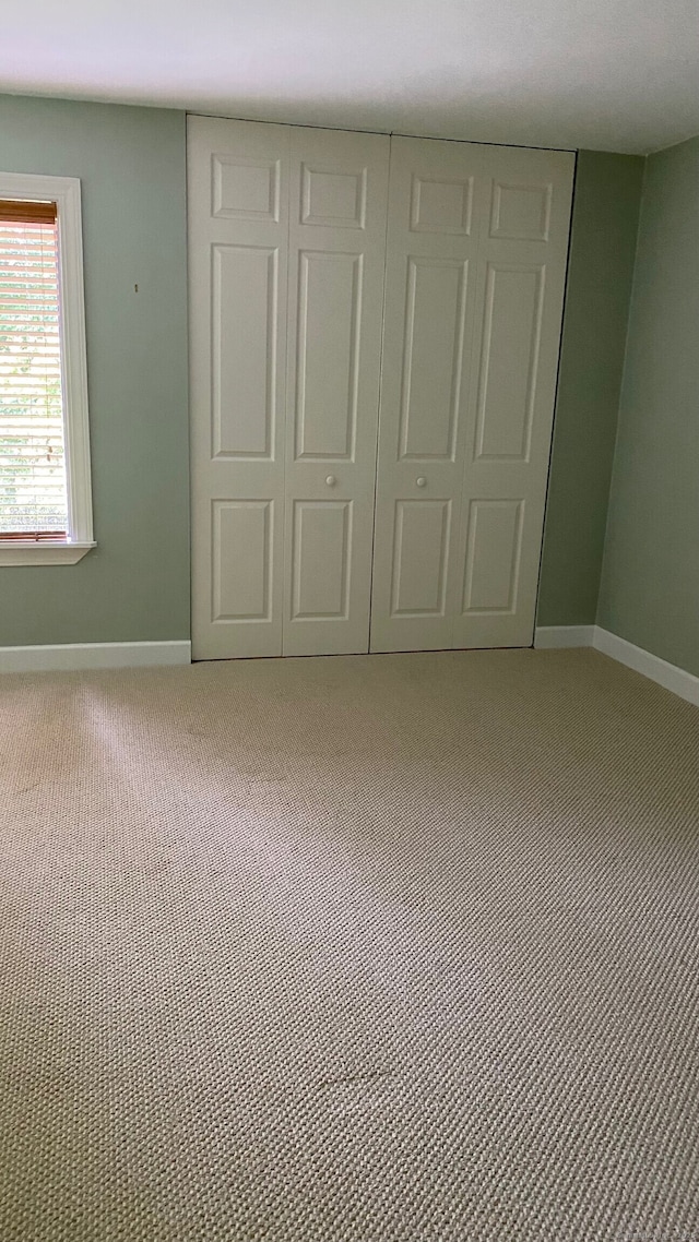 unfurnished bedroom featuring baseboards, carpet, and a closet