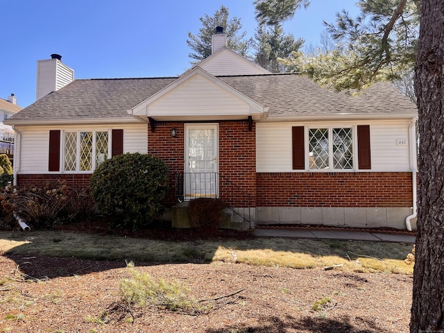 view of front of home featuring a shingled roof, brick siding, and a chimney