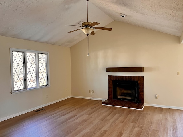 unfurnished living room featuring visible vents, a tiled fireplace, vaulted ceiling, wood finished floors, and a textured ceiling