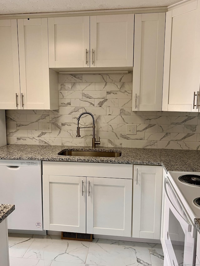 kitchen with white appliances, marble finish floor, stone counters, and a sink