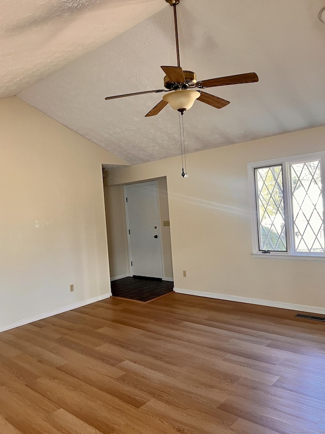 unfurnished room featuring vaulted ceiling, wood finished floors, baseboards, and a textured ceiling