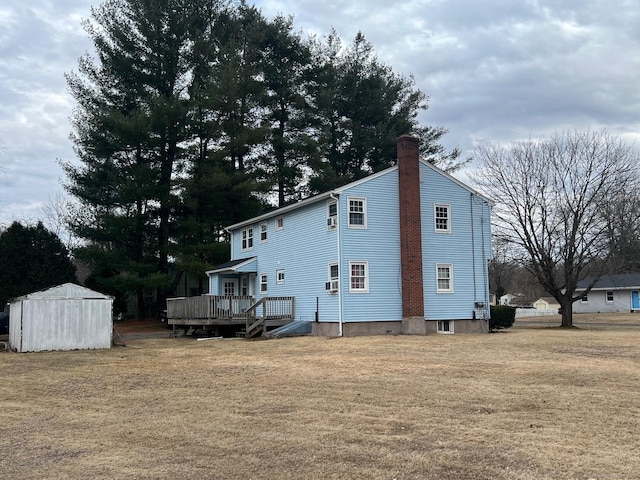 rear view of property with a storage unit, an outbuilding, a yard, and a chimney