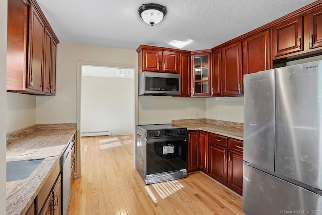 kitchen featuring dark brown cabinets, glass insert cabinets, a baseboard heating unit, light wood-type flooring, and stainless steel appliances